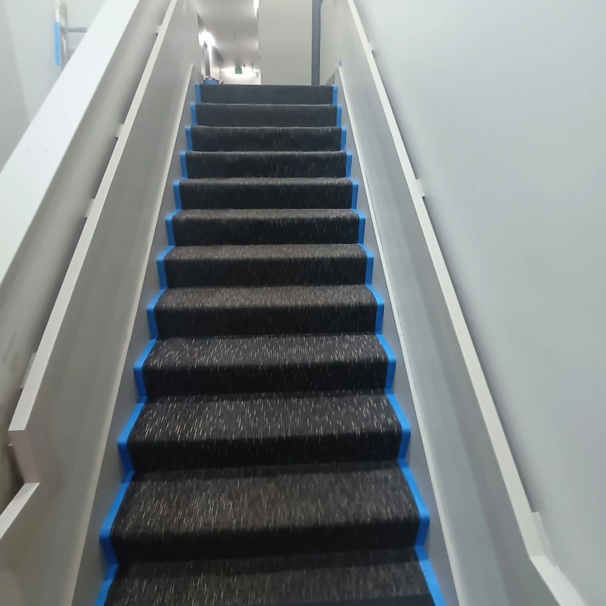 Staircase painting in San Jose, CA: carpeted stairs taped off beside a painted white rail