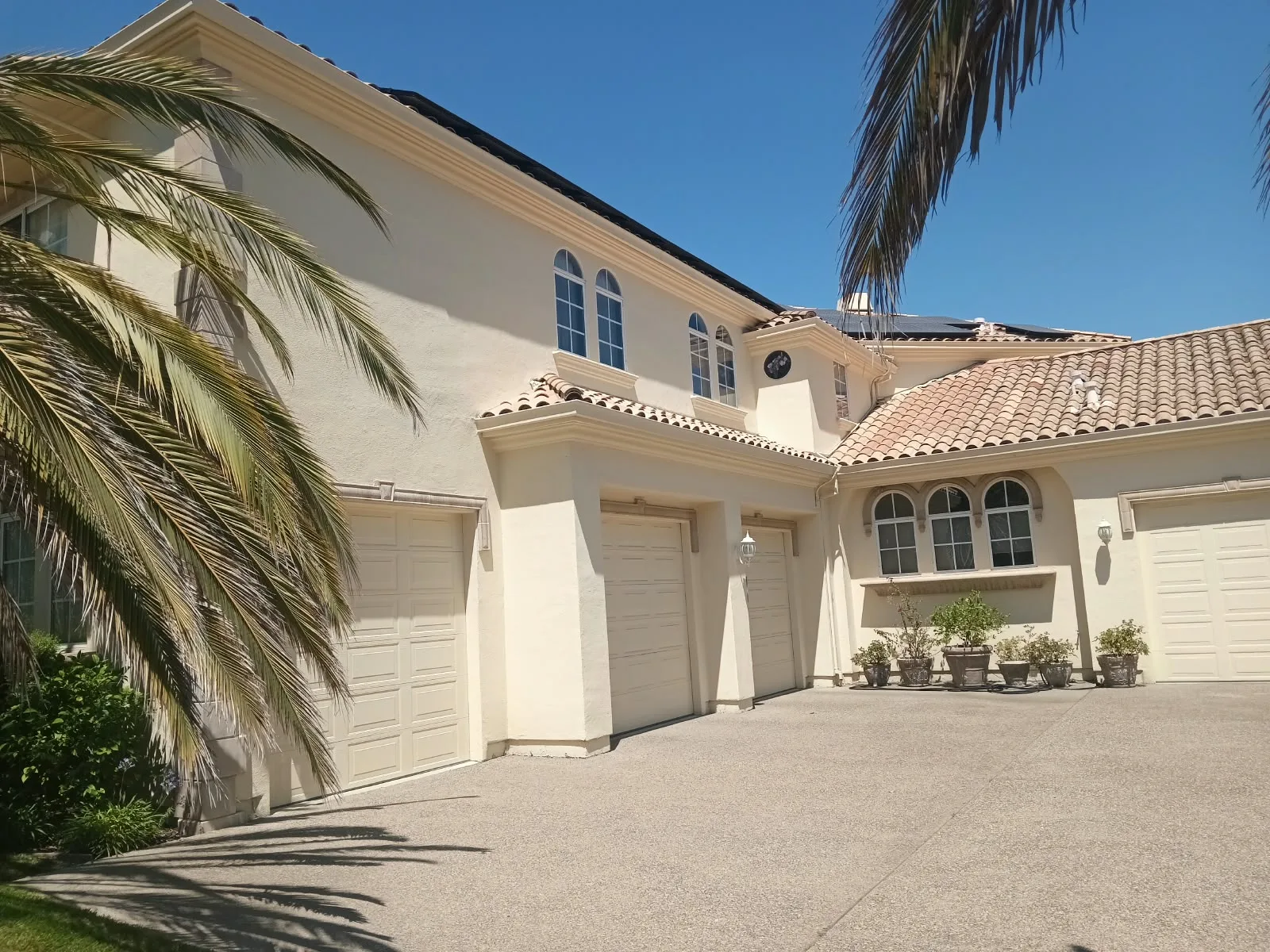 Exterior painting in San Jose, CA: cream stucco home with tile roof and three-car garage