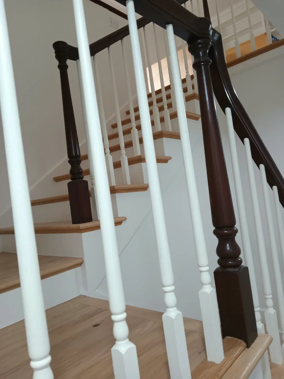 Staircase painting in San Jose, CA: white balusters and stained handrail