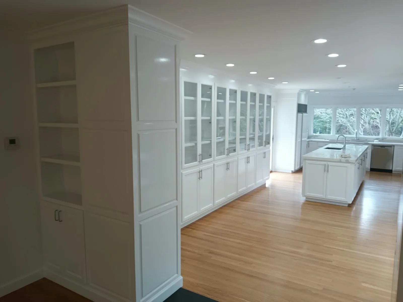 Cabinet painting in San Jose, CA: white built-in cabinets leading into an open kitchen