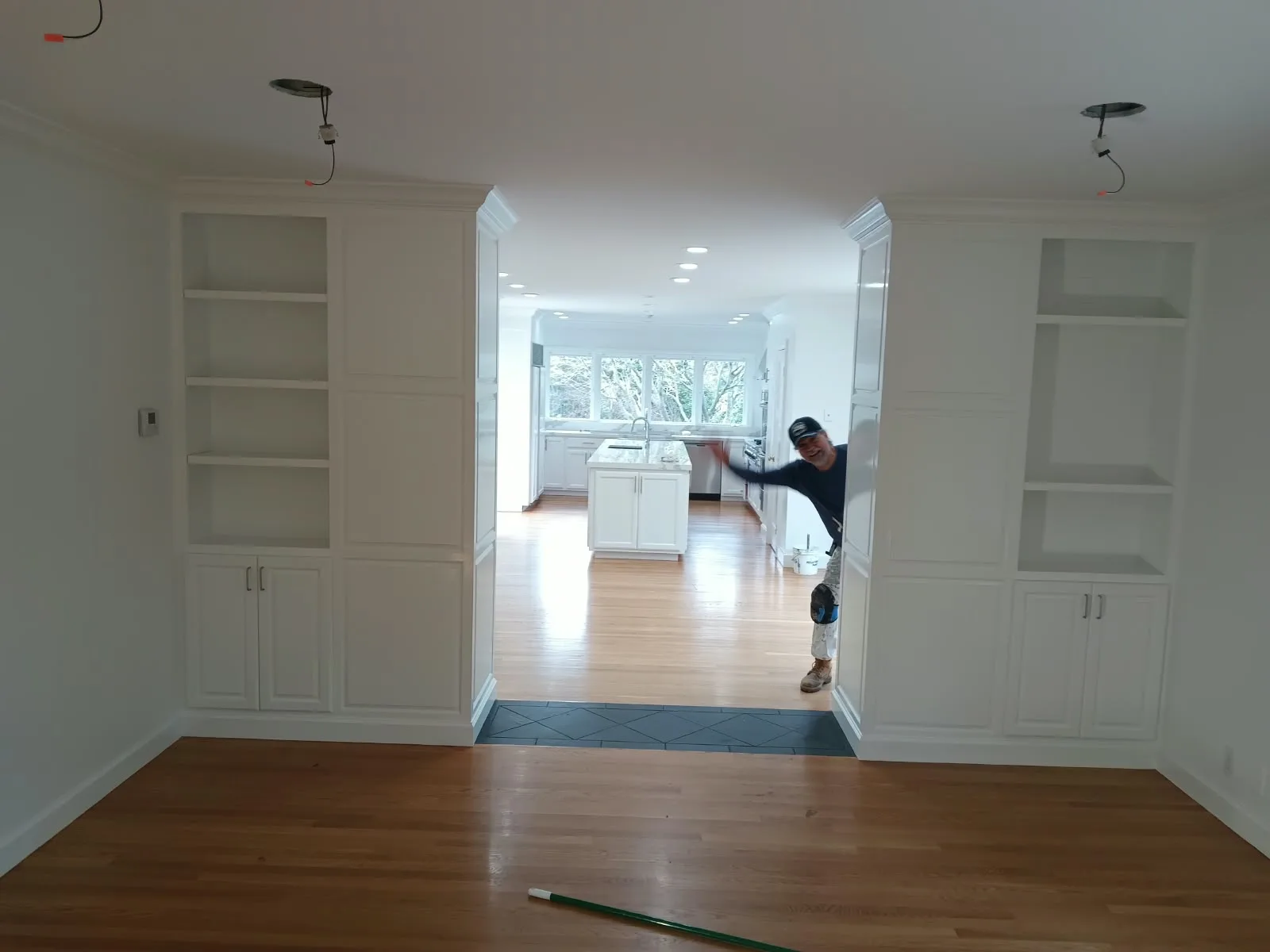 Interior painting in San Jose, CA: white built-in shelving and cabinets with painter in the doorway