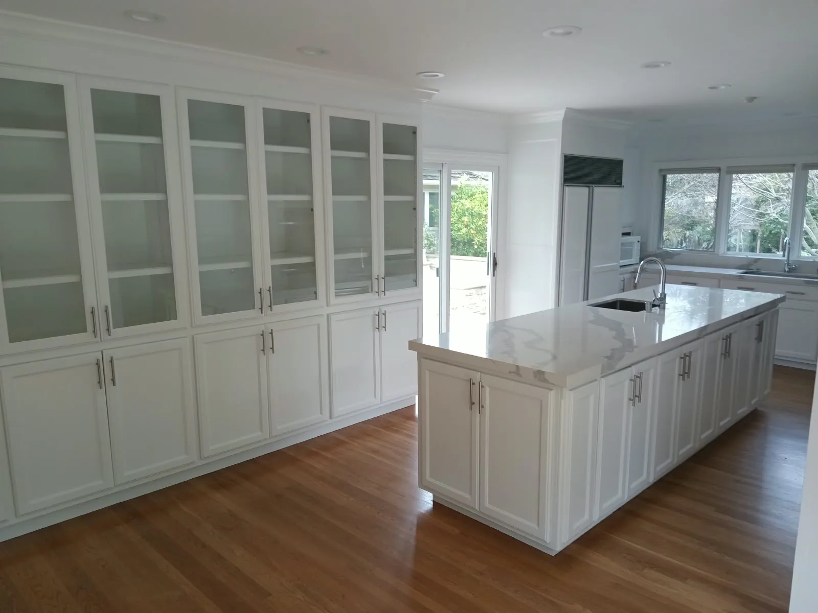 Cabinet painting in San Jose, CA: wall of white glass-front cabinets and large island